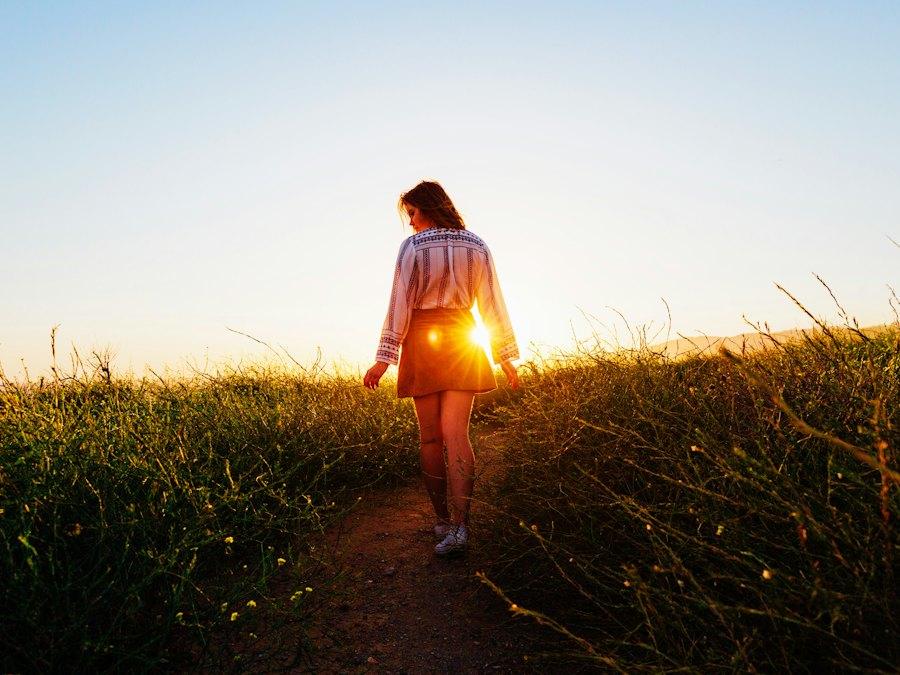 A woman walking along a path through a golden field at sunset
